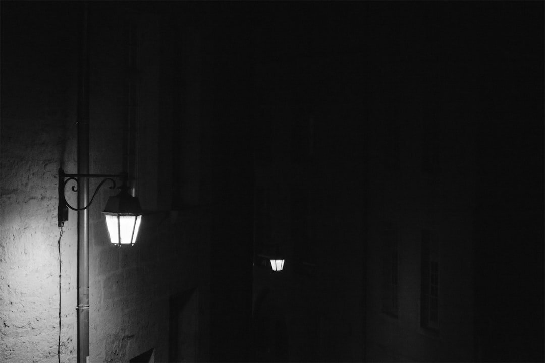 Single glowing street lamp on an empty foggy cobblestone street at night
