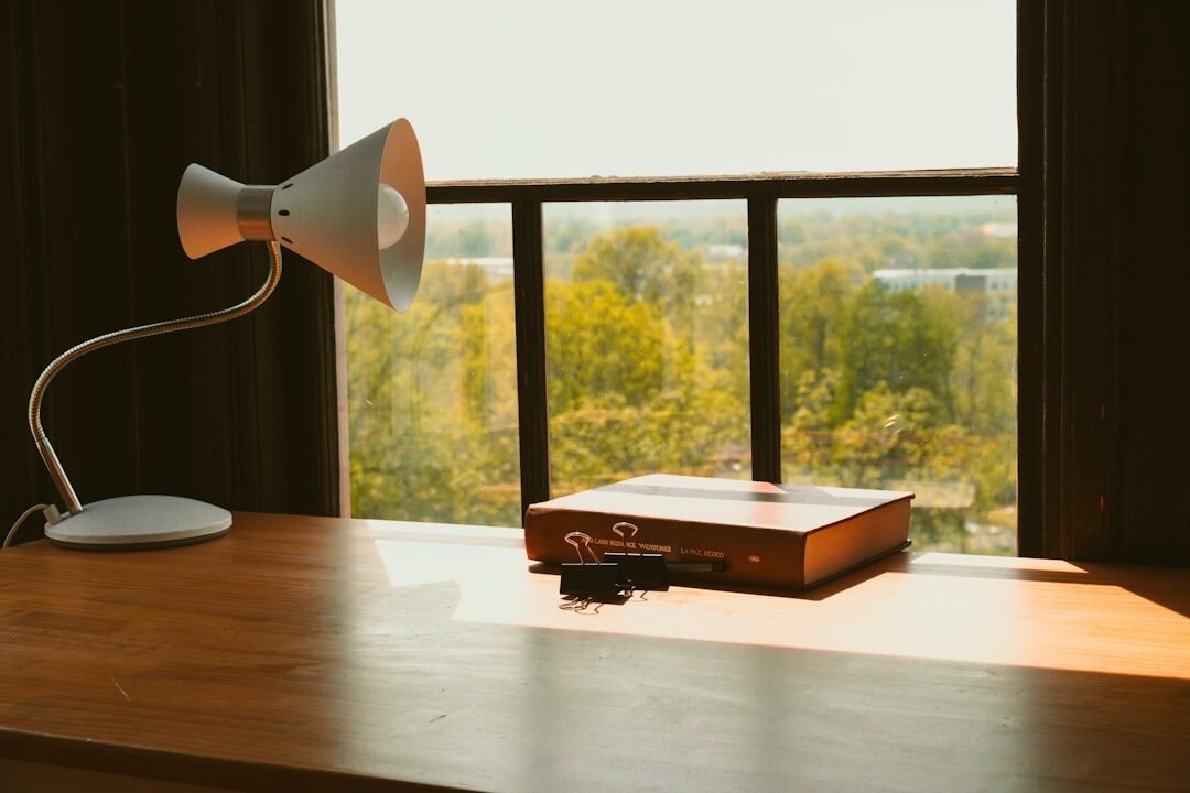 Vintage wooden desk with a typewriter, notebook and lamp near a window